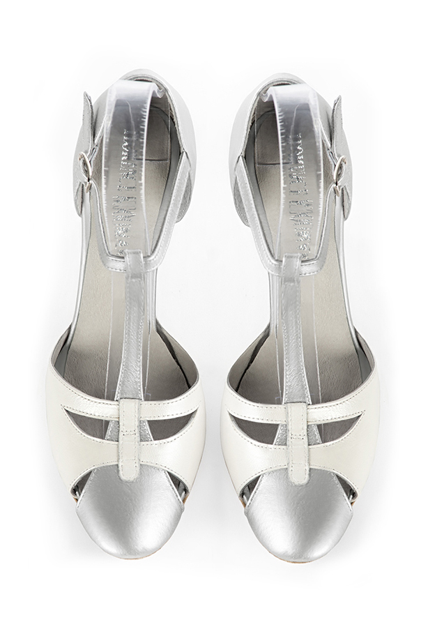 Salomés habillées, élégantes et raffinées, ouvertes sur les côtés, coloris argent platine et blanc pur. Bout rond. Haut. Talon fin. Cérémonie, soirée, cocktail, évènementiel. Personnalisation : Choix des cuirs, 
                des couleurs et des talons. Petites et grandes pointures. - Florence KOOIJMAN