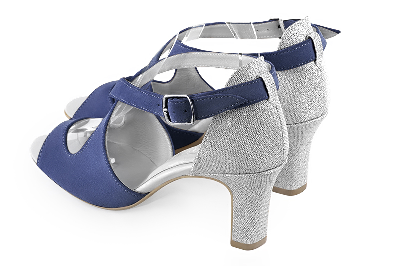 Chaussure femme ouverte : Sandale avec l'arrière fermé et des brides croisées sur le cou-de-pied couleur bleu indigo et argent platine. Talon haut. Talon trotteur. Bout rond - Florence KOOIJMAN