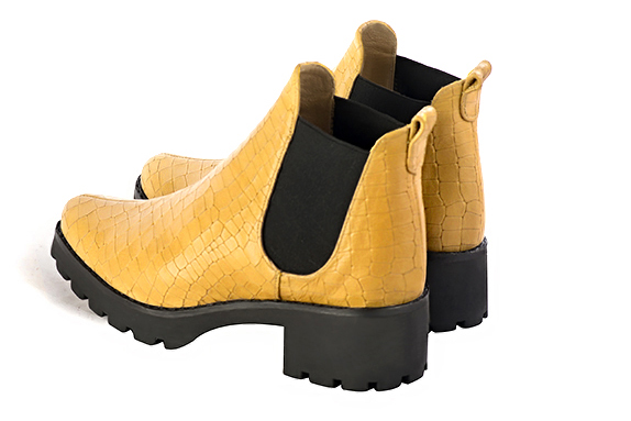Boots femme : Boots élastiques sur les côtés couleur jaune ocre et noir mat. Bout rond. Semelle gomme petit talon. Vue arrière - Florence KOOIJMAN