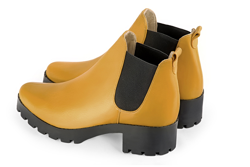 Bottines élégantes et raffinées avec des élastiques sur les côtés, coloris jaune ocre et noir mat. Bout rond. Semelle gomme mi-haut. Personnalisation : Choix des cuirs, des couleurs et des talons. Cou-de-pied sur mesure. - Florence KOOIJMAN