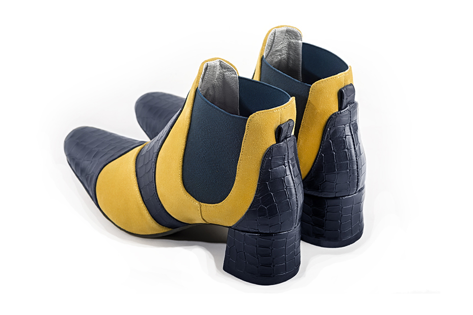 Bottines bicolores élégantes et raffinées avec des élastiques sur les côtés, coloris bleu marine et jaune soleil. Bout rond. Mi-haut. Talon évasé. Personnalisation : Choix des cuirs, des couleurs et des talons. Cou-de-pied sur mesure. - Florence KOOIJMAN